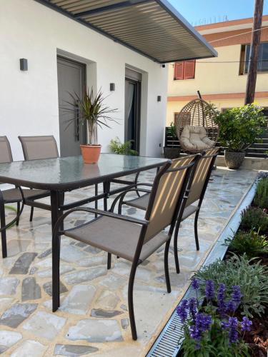 un patio con mesa, sillas y flores en Casa De Afrodite en Argostoli