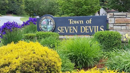a sign for a town of seven devils in a garden at A Slice of High Country Heaven, Seven Devils Condo in Seven Devils