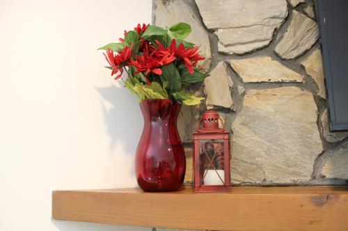 a red vase with flowers and a candle on a shelf at A Slice of High Country Heaven, Seven Devils Condo in Seven Devils