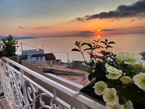 a balcony with flowers and a sunset on the water at B&B bella vista in Pizzo