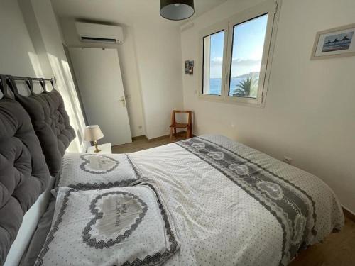 - une chambre avec un lit doté d'une couverture blanche et d'une fenêtre dans l'établissement Appartement bord de mer avec garage, à Menton