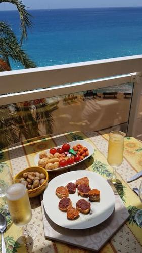 une table avec deux assiettes de nourriture et des verres de jus d'orange dans l'établissement Appartement bord de mer avec garage, à Menton