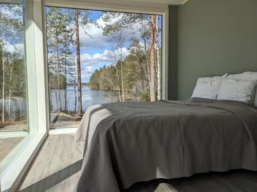 sypialnia z łóżkiem i dużym oknem w obiekcie Lakehouse Juolas w mieście Mäntyharju