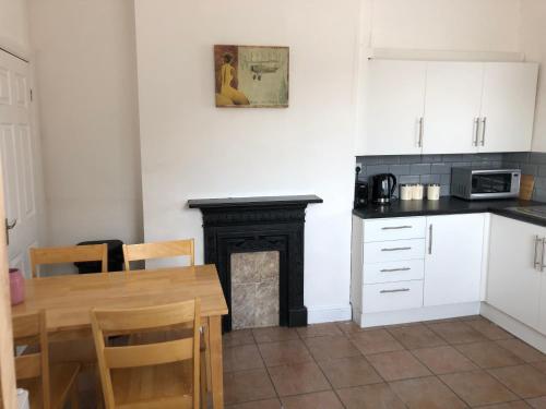 a kitchen with a table and a fireplace at Hilltop Cottage in Renishaw