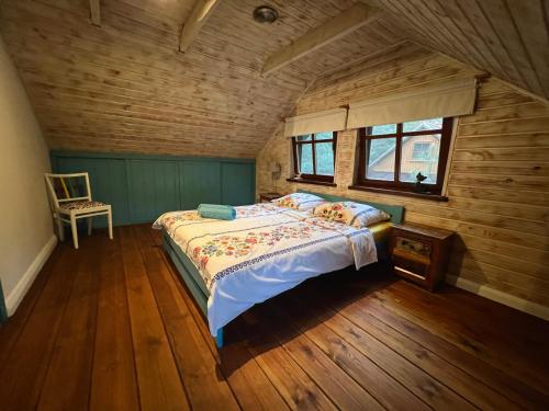 ein Schlafzimmer mit einem Bett in einem Holzzimmer in der Unterkunft Sosnowy Zakatek in Zyzdrojowy Piecek