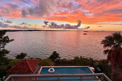 einen Sonnenuntergang über einem Wasserkörper mit einem Pool in der Unterkunft Turquoise Haven Villa in Providenciales