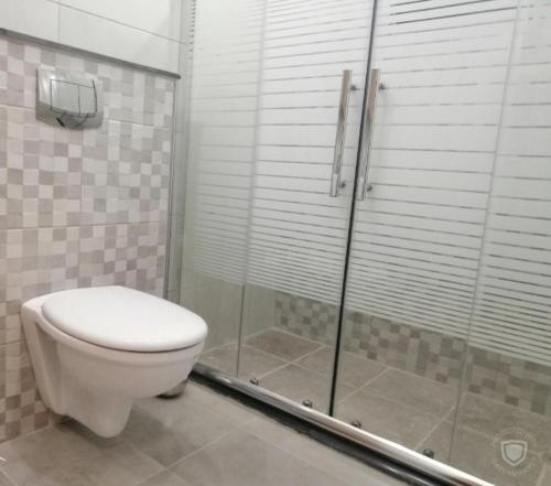 a bathroom with a toilet and a glass shower at Amazing one Bedroom Apartment in Amman Elwebdah 8 in Amman