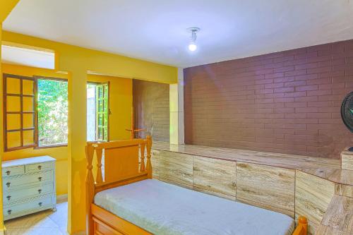 a bedroom with a wooden bed and yellow walls at Loft em Maricá RJ - Araçatiba in Maricá