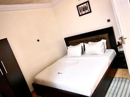a bedroom with a bed with white sheets and pillows at Apartment A- 2 Bedroom Apartment) Hillside Gardens in Lagos