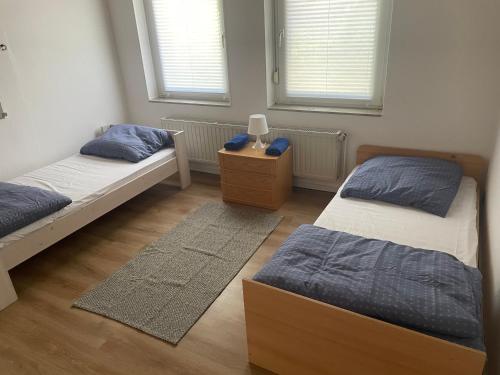 1 dormitorio con 2 camas, mesita de noche y 2 ventanas en Ruhiges zentral gelegenes Apartment in Gütersloh, en Gütersloh