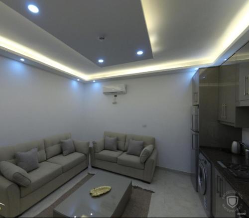 a living room with couches and a table and a kitchen at Amazing one Bedroom Apartment in Amman Elwebdah 1 in Amman