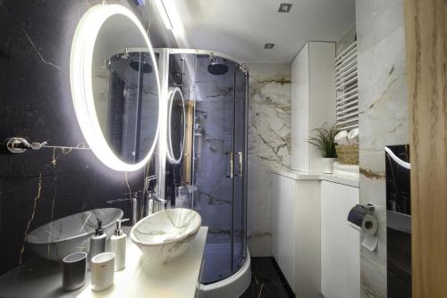 a bathroom with a sink and a shower with a mirror at Apart Dwudziestolecie in Wadowice