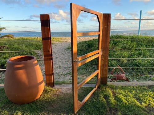 a wooden door and a pot next to a fence at Casa Kala "Uma experiência beira-mar" in Porto De Galinhas