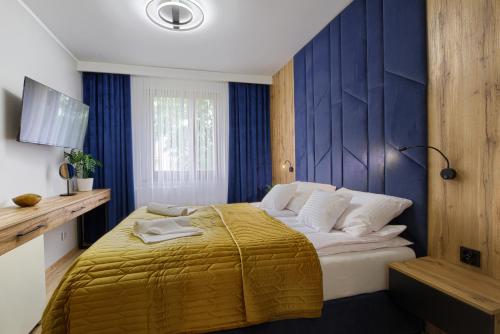 a bedroom with a large bed with a yellow blanket at Apart Dwudziestolecie in Wadowice