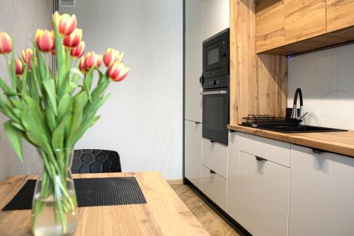 a vase of flowers on a wooden table in a kitchen at Apart Dwudziestolecie in Wadowice