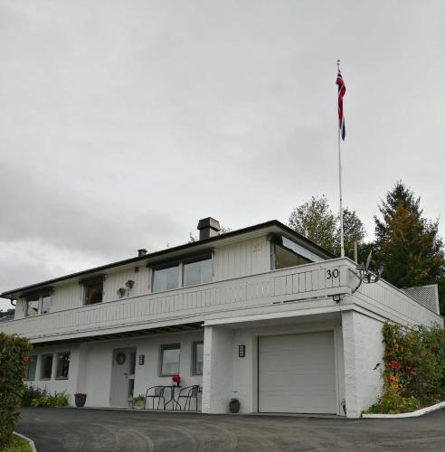 a white building with a flag on top of it at Ett-to rom til leie i et privat hus in Brumunddalen