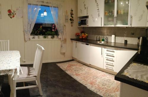 cocina con armarios blancos, mesa y ventana en Ett-to rom til leie i et privat hus en Brumunddal