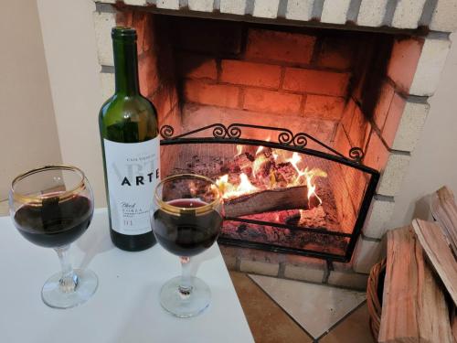 two glasses of red wine next to a fireplace at Pousada do Pórtico in Gramado