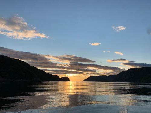 a sunset over a river with mountains in the background at Reistad Ranch in Hidra