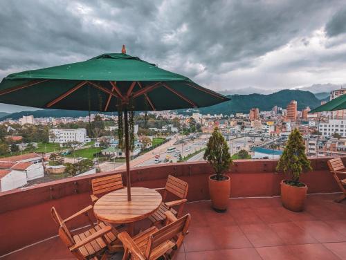 a table and chairs with an umbrella on a balcony at Hotel Charlotte Suite 26 in Bogotá