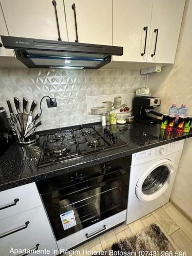 a kitchen with a stove and a washing machine at Apartament cu o camera de Lux cu Jacuzzi/Constelatie complet utilat acceptam plata cu cardul de vacanta in Botoşani