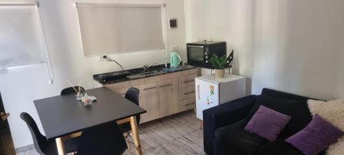 sala de estar con sofá, mesa y cocina en Departamento Costa Paz en Villa Carlos Paz