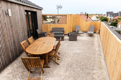 a wooden table and chairs on a patio at La Terrasse du Sentier in Sangatte