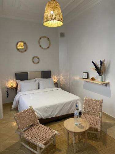 um quarto com uma cama, 2 cadeiras e uma mesa em Riad Hanya em Marraquexe