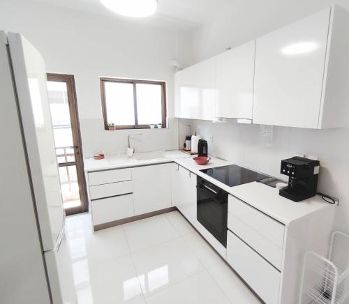 una cocina blanca con armarios blancos y un aparato negro en Central condo with homegym, next to the main beach, en Rodas