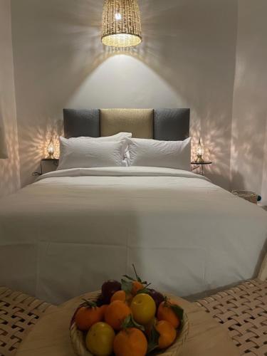 a bed with a bowl of fruit on a table at Riad Hanya in Marrakech
