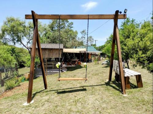 a swing set with a bench and a building at Sítio pousada e Refúgio lazer e eventos in Santana do Livramento