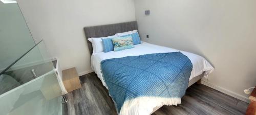 a small bedroom with a bed with a blue blanket at Moher Lodge in Liscannor