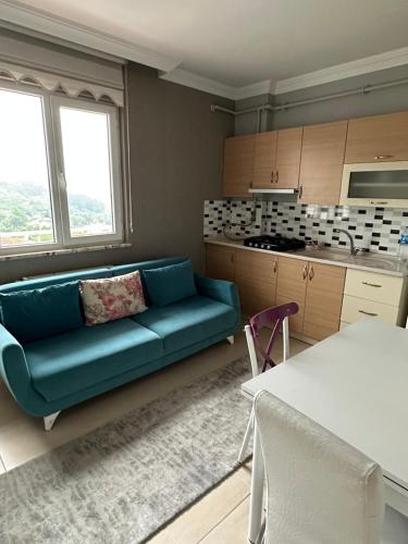 sala de estar con sofá azul y cocina en GÖKTÜRK APART, en Trabzon