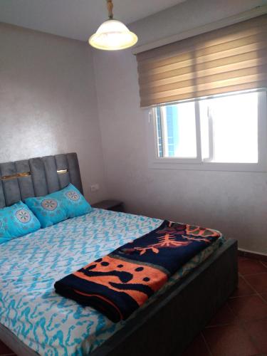 MIRADOR GOLF 02 N°B15 CABO NEGRO في تطوان: غرفة نوم مع سرير ووسائد زرقاء ونافذة
