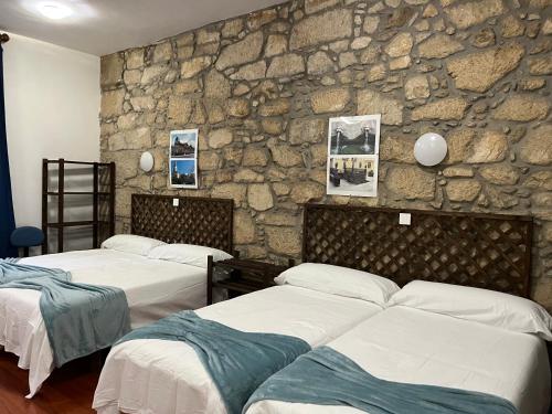 two beds in a room with a stone wall at Fogar de Breogán "LOFT NÓS" in Caldas de Reis