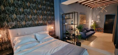 - une chambre avec un grand lit blanc et un canapé dans l'établissement Boutique Suites, à Arcos de la Frontera