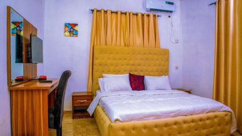 sypialnia z łóżkiem z żółtym zagłówkiem i biurkiem w obiekcie KUNN Apartments w Asabie