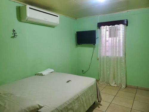 um quarto com uma cama branca e uma janela em Apartamentos y Hostal RUDON #4 em Puerto Cortes