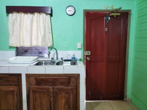 uma cozinha com um lavatório e uma porta vermelha em Apartamentos y Hostal RUDON #4 em Puerto Cortes
