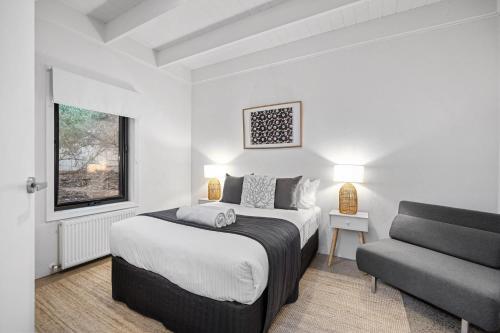 a white bedroom with a bed and a couch at Sorrento Beach House in Sorrento