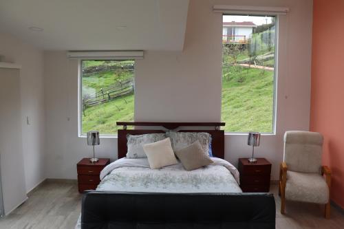 um quarto com uma cama, uma janela e uma cadeira em Glamping en Granja Campo Hermoso em Cogua