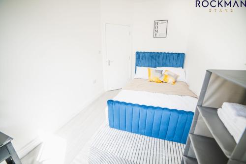 Schlafzimmer mit einem Bett mit blauer Bettwäsche und Kissen in der Unterkunft 12B Alexandra Street - Stylish Apartment in the Heart of Southend on Sea by Rockman Stays in Southend-on-Sea