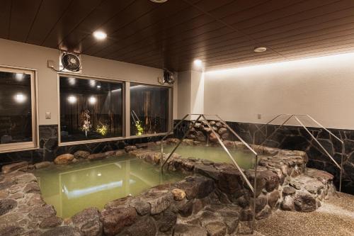 a jacuzzi tub in a room with rocks at Hotel Arthur KITAHAMA BASE in Beppu