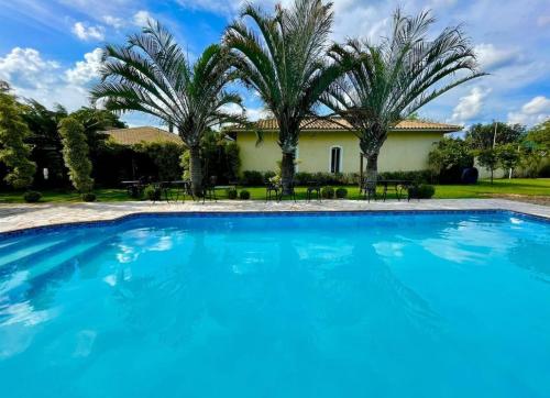 a pool in front of a house with palm trees at Casa de Férias em Atibaia Piscina Climatizada in Atibaia