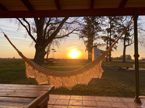 a hammock in a field with the sunset in the background at Estancia Santa Margarita 1873 in Junín