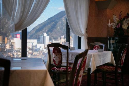 a dining room with a table and chairs and a window at Hotel Arthur KITAHAMA BASE in Beppu