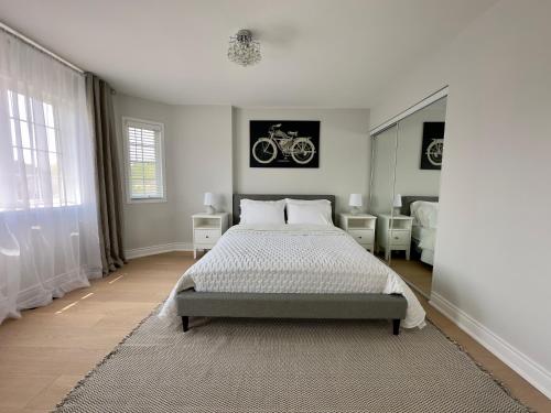 a white bedroom with a bed and a bicycle on the wall at Lavish 4BR House Near Simcoe Lake & FH Resort in Innisfil
