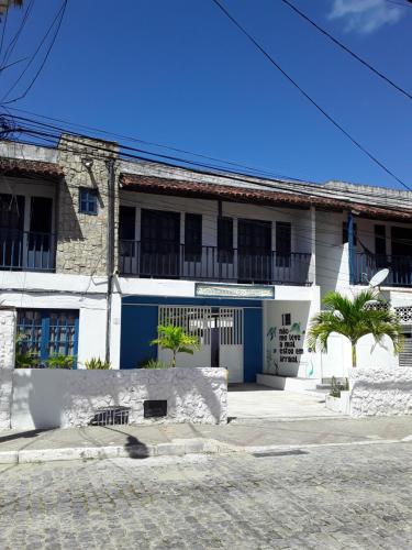 a white building with blue doors and palm trees at Santorini Flats in Arraial do Cabo