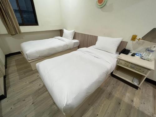 two beds in a small room with a table and a bed sidx sidx at 日日 Meworld in Beigang