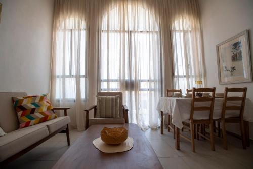 een woonkamer met een tafel, stoelen en ramen bij GOLANI8 in Haifa